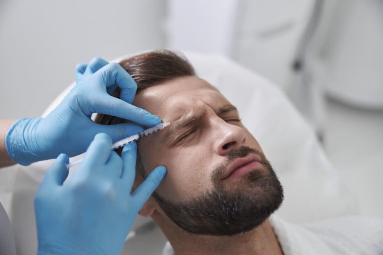 бородатому мужчине делают косметическую процедуру, вводят филлер