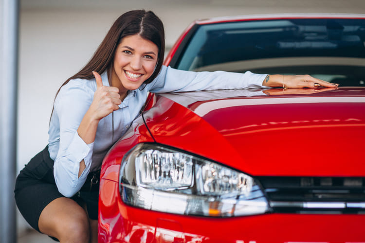 молодая женщина покупает красный автомобиль